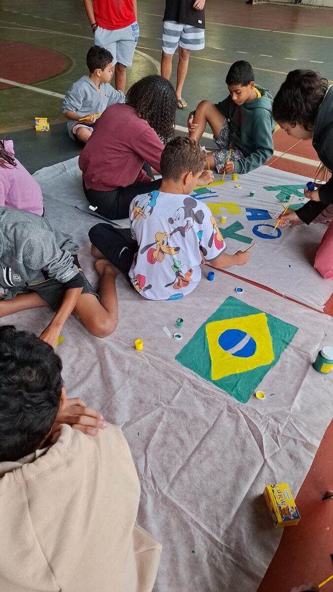 Crianças pintando bandeira do Brasil em atividade de artesanato