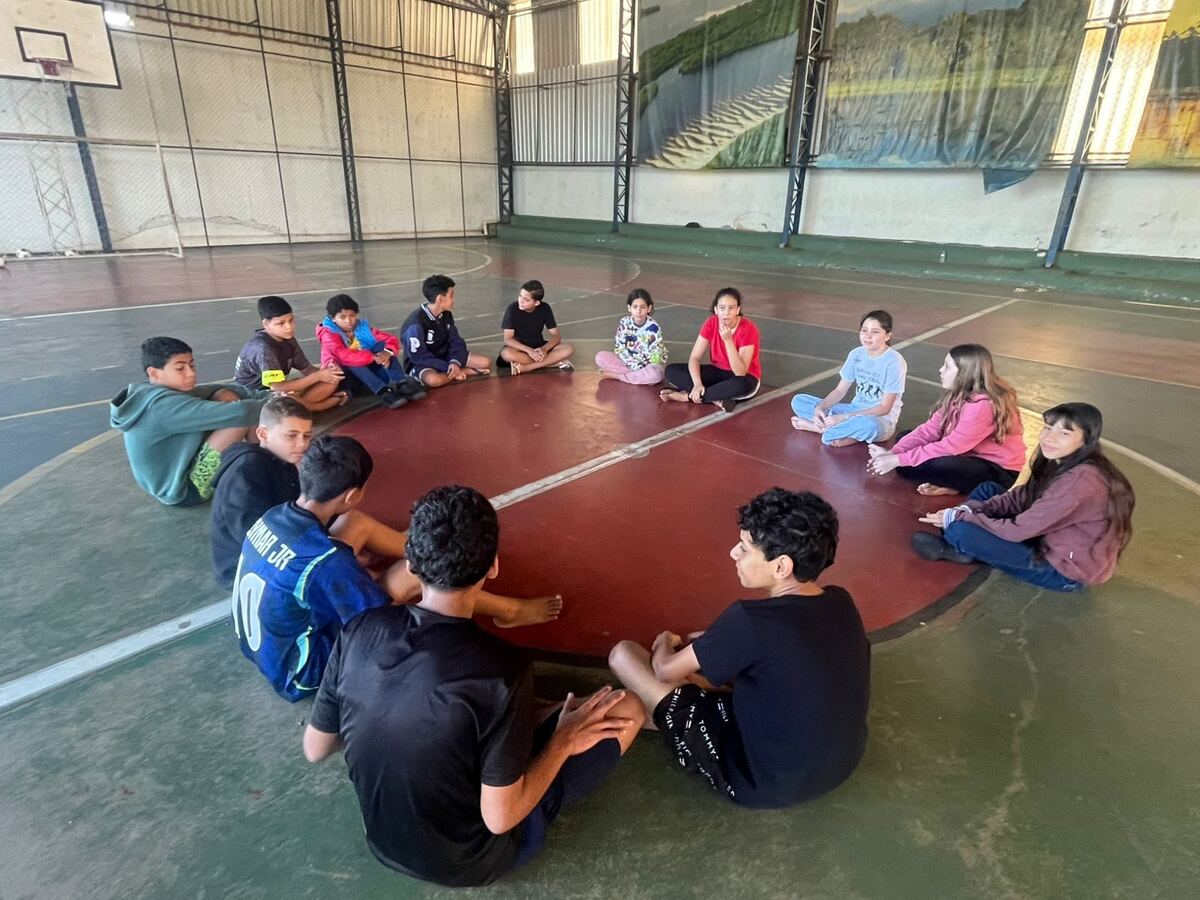 Crianças sentadas em roda conversando na quadra do SEPIN